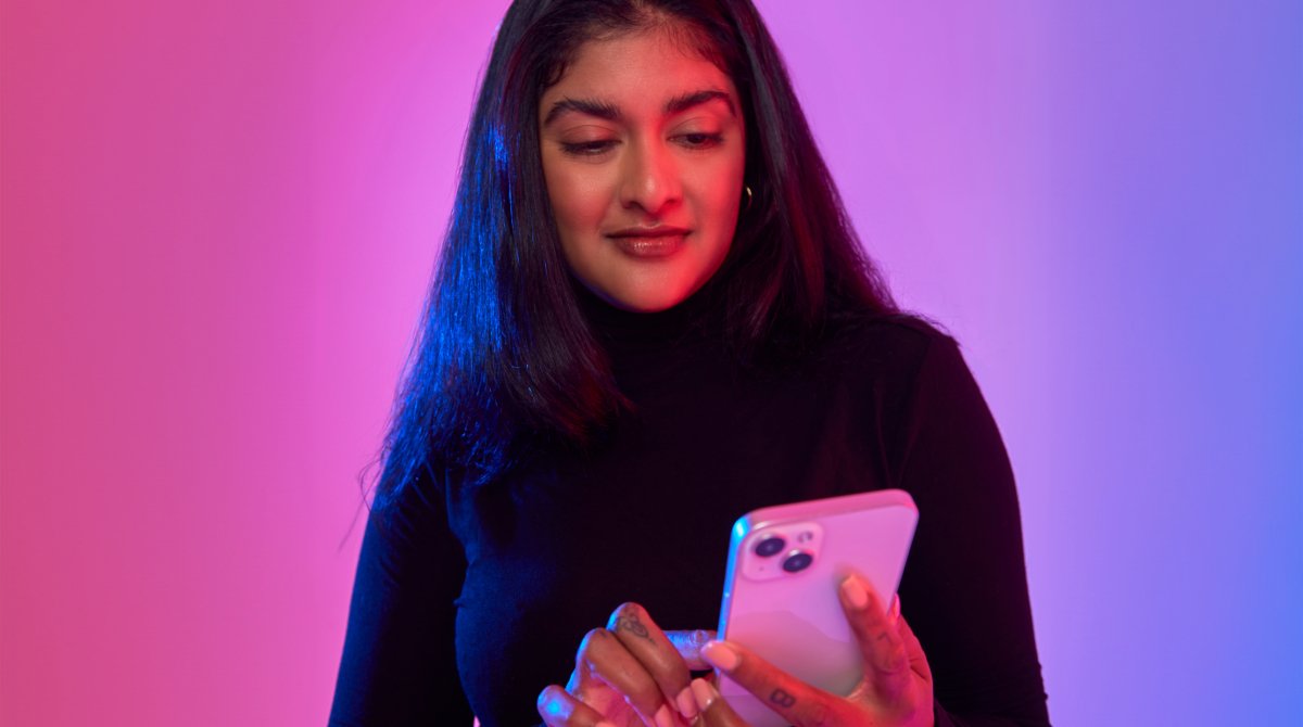 Woman standing as she scrolls through her phone.