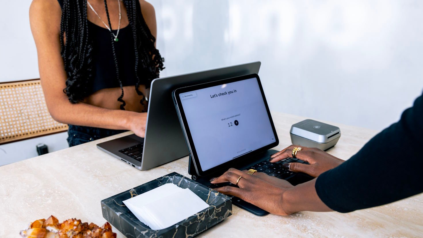 A beauty business employee checks a client in on a tablet.