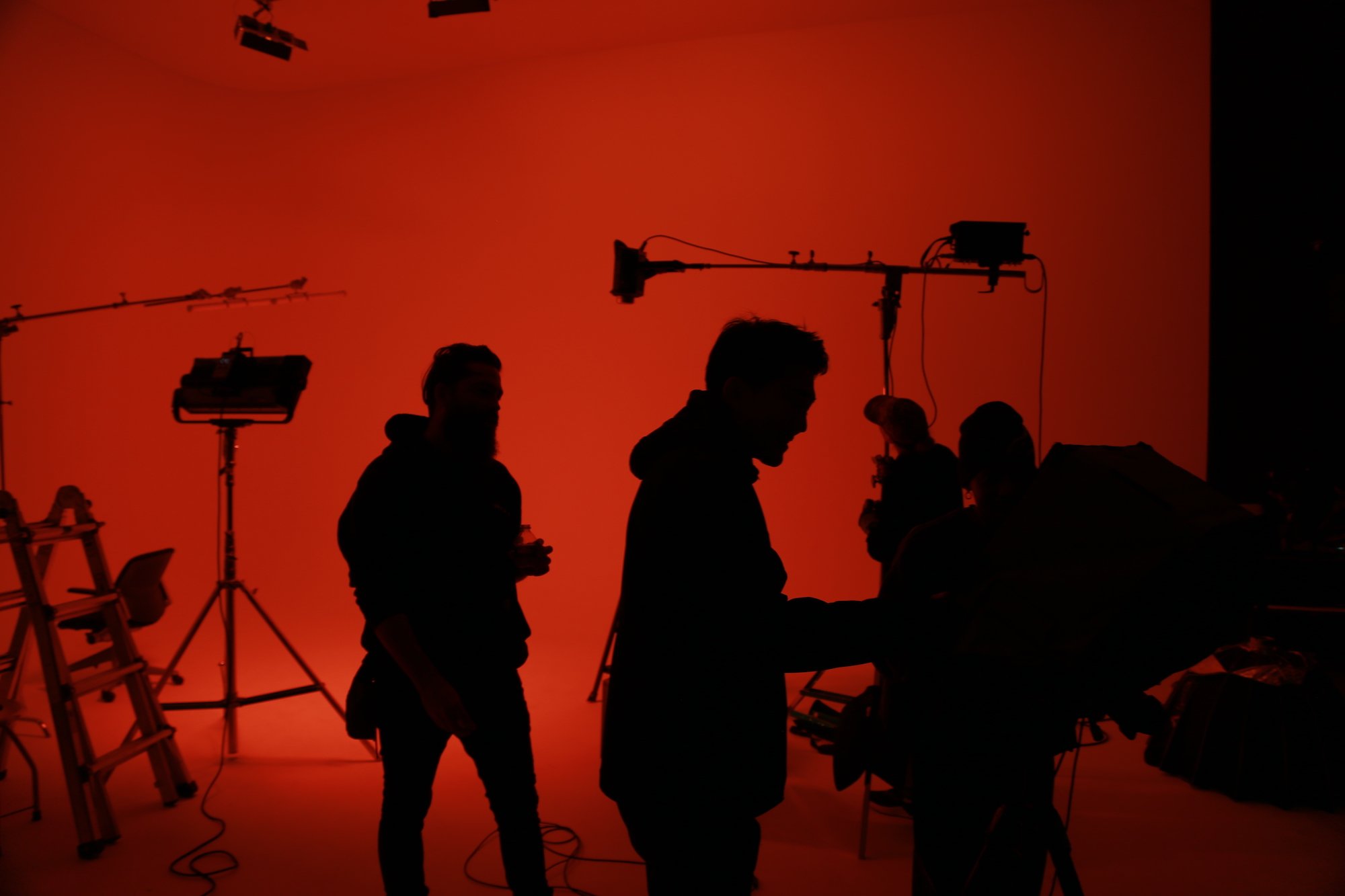 Two women look at a tablet while standing in front of the set of a photoshoot.