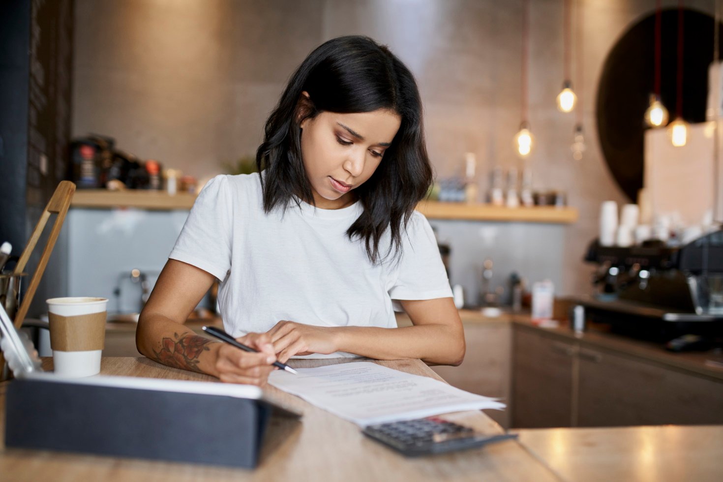 A woman sits at a desk filling out a tax form.