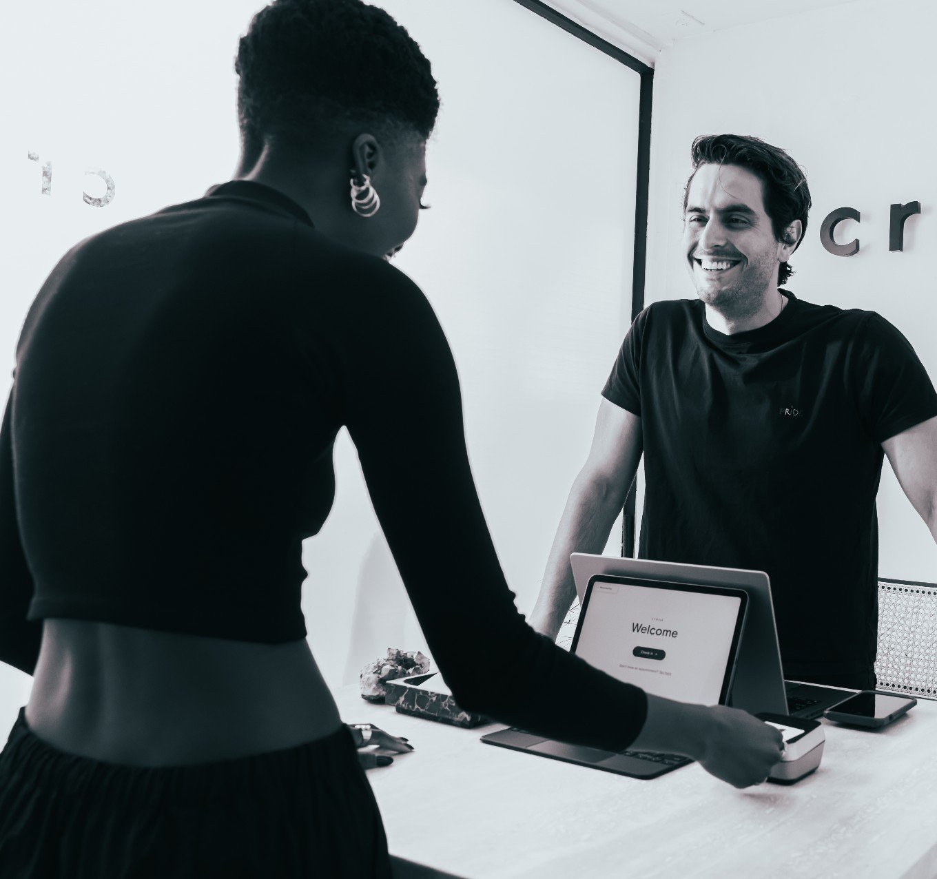 A satisfied customer uses a tablet at a reception desk to complete a transaction. 