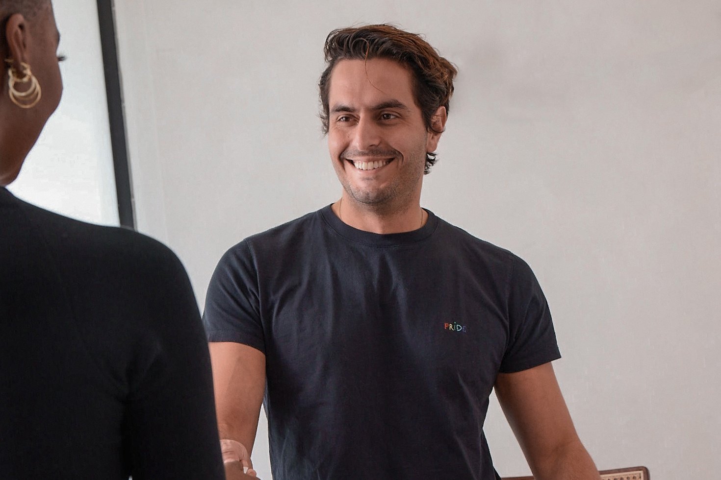 A salon stylist smiles as he greets a client.