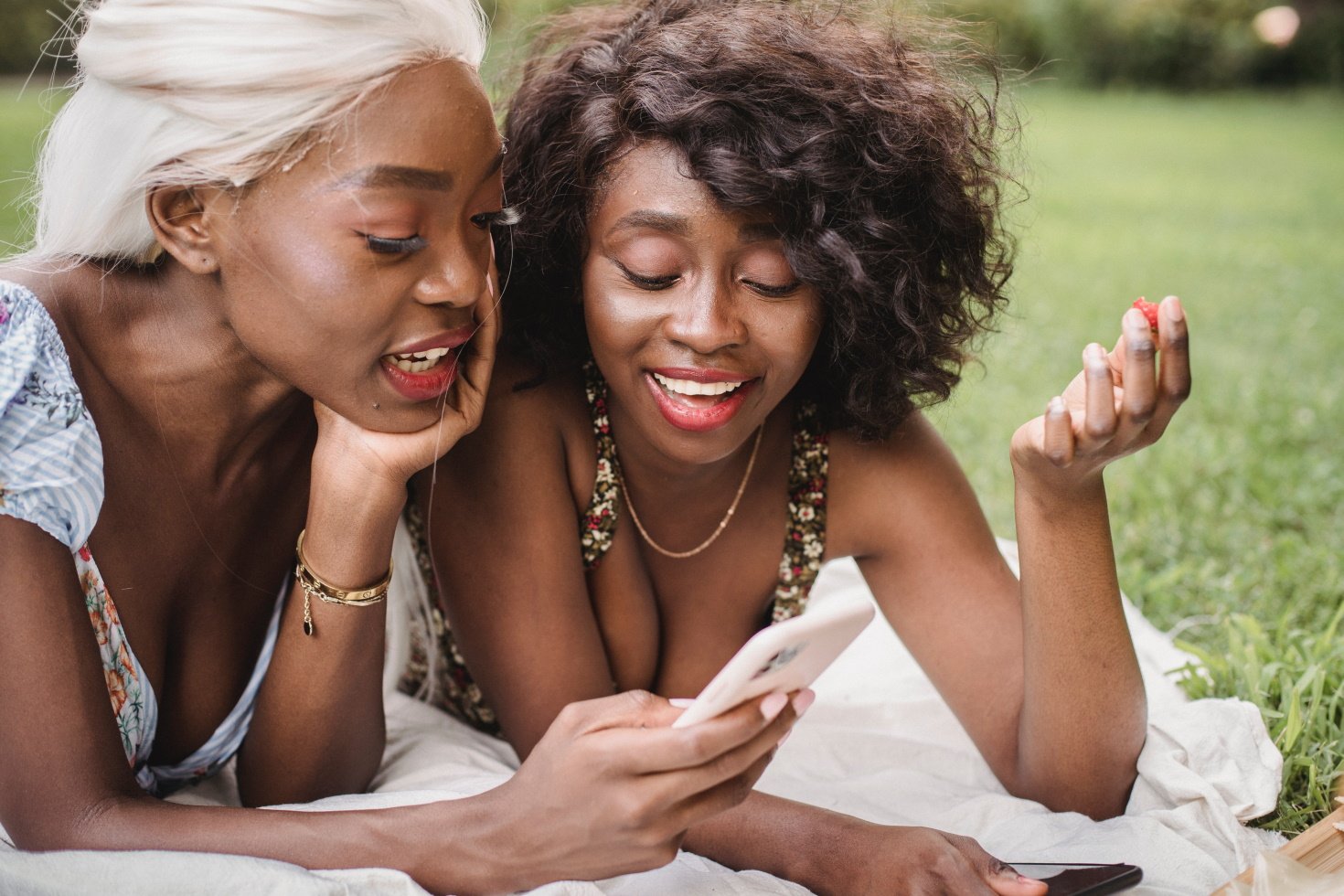 Two women smile as they both look at a smartphone.