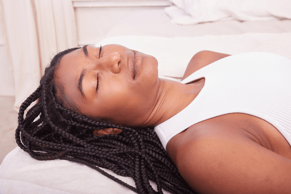 A woman lays on a massage table at a day spa with her eyes closed as she await her treatment.