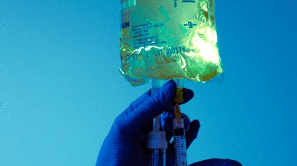 A provider adds an injection to an IV bag.